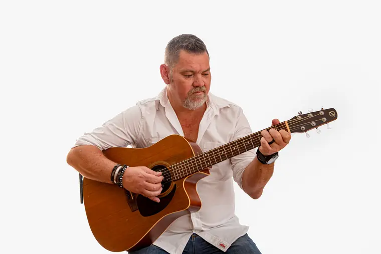 Wynand Strydom speel kitaar teen ’n wit agtergrond